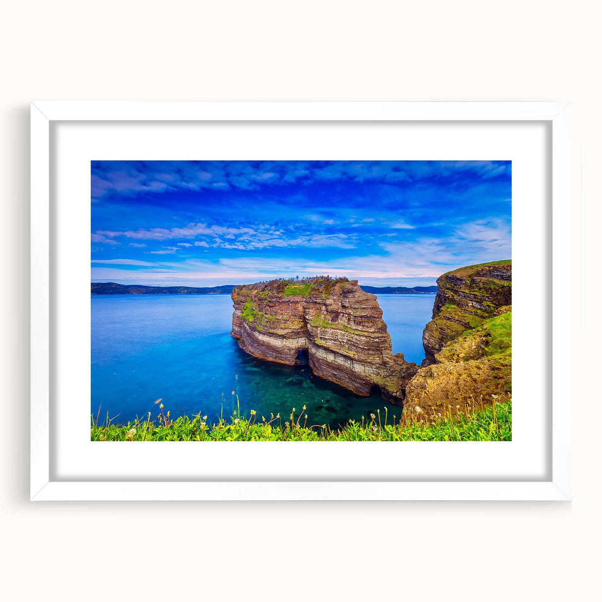 Abstract art print of Newfoundland scenery in muted green and blue tones, framed with a white mat.
