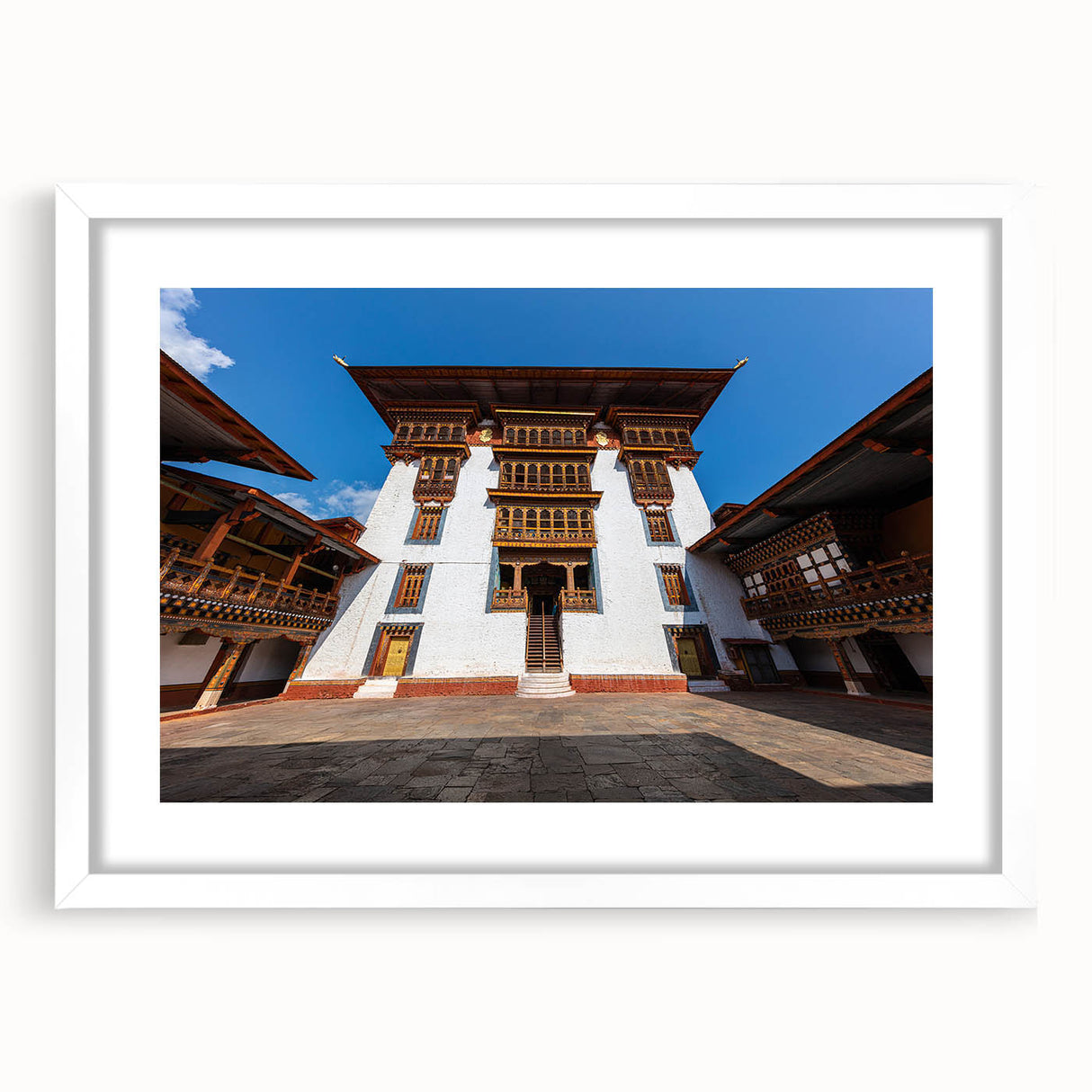 Abstract art print of Bhutan scenery in muted earth tones on a framed white mat, ideal for dining room decor.