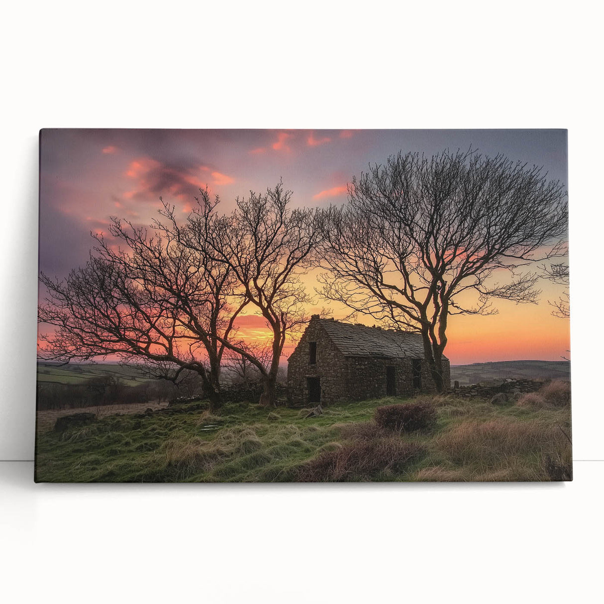 Stretched canvas artwork depicting a serene landscape scene with a rustic barn, leaning against a neutral wall, capturing a tranquil rural atmosphere.