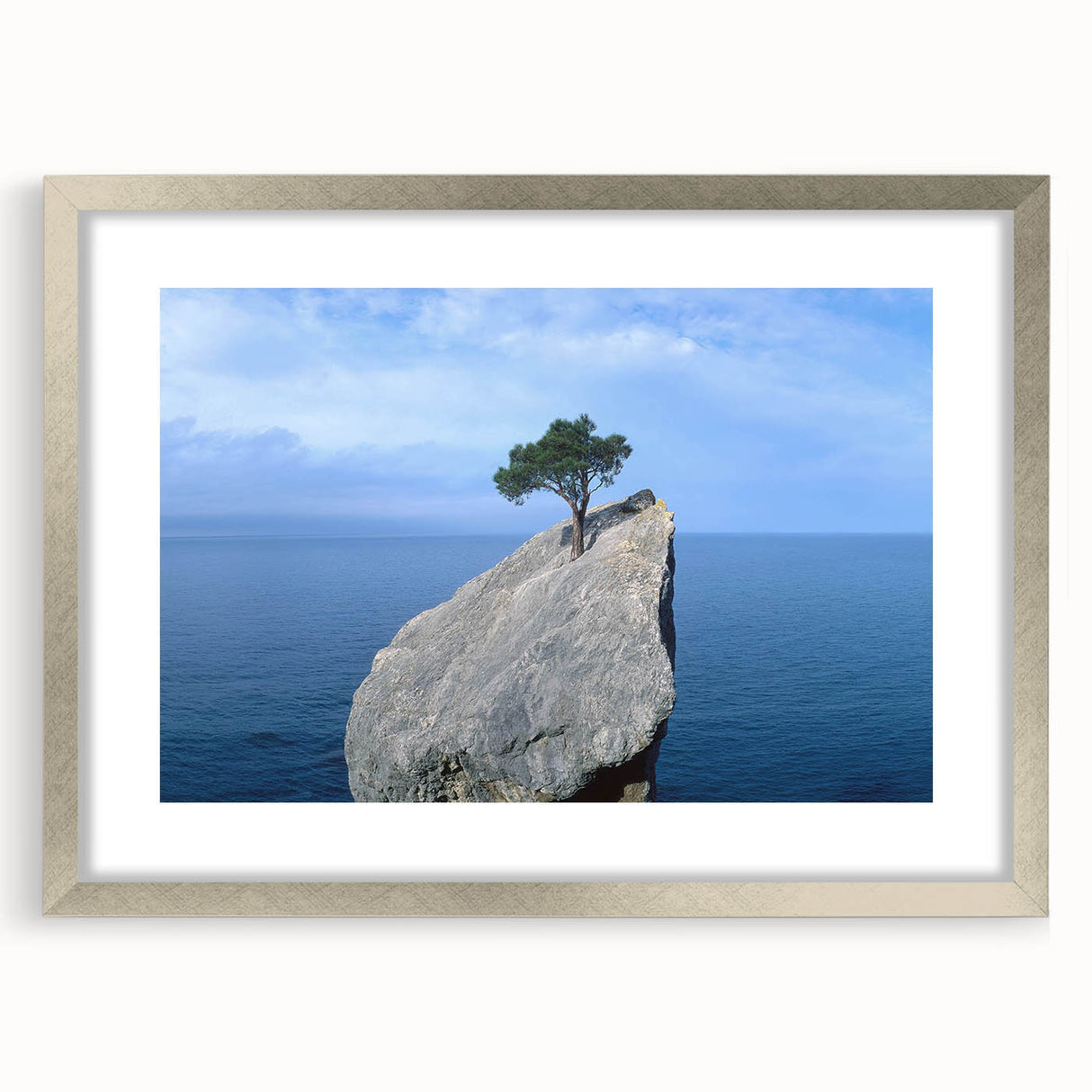 Framed artwork showcasing a serene landscape with rocks, surrounded by a silver mat and frame, perfect for home decor or artistic display in modern interiors.