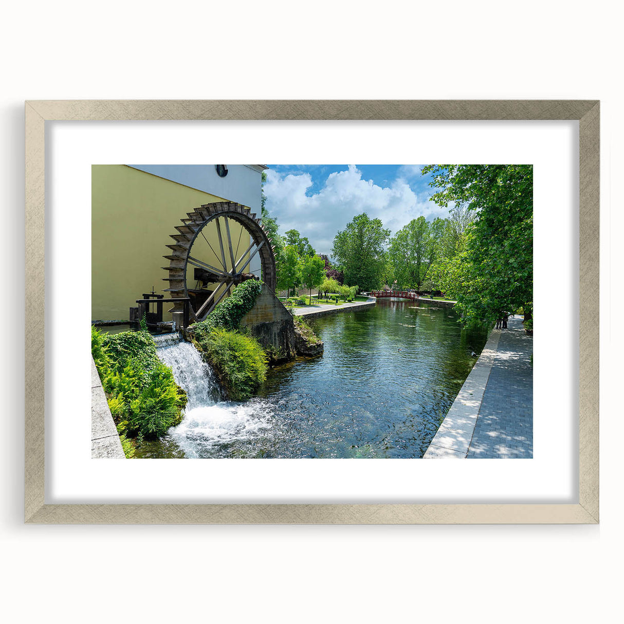Framed wall art depicting a serene watermill landscape, featuring a silver mat and frame. Ideal for enhancing home decor with nature-inspired elegance.