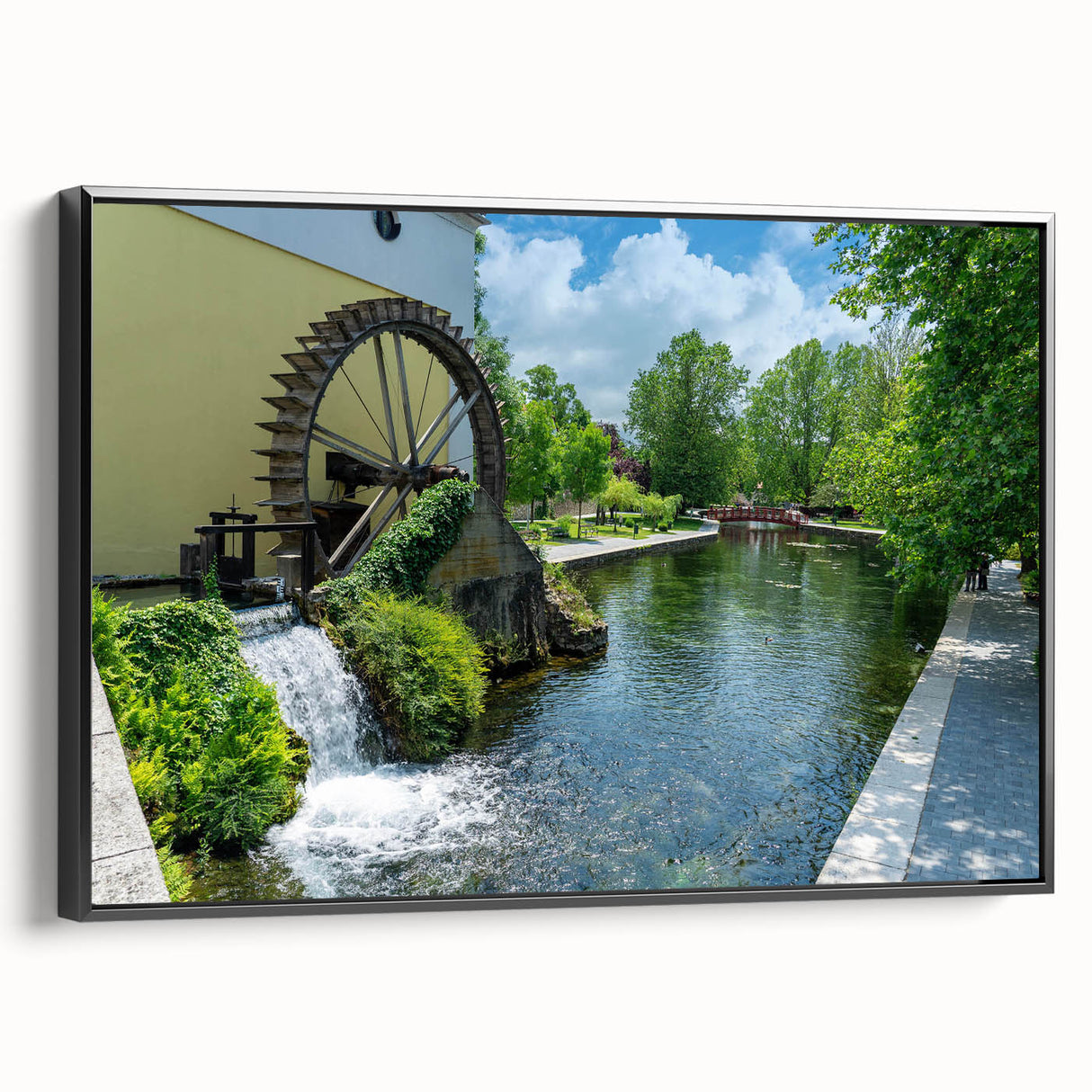 Framed canvas wall art showcasing a serene watermill landscape design, featuring lush greenery and a tranquil water scene, with a sleek black frame enhancing its elegance. Perfect for home decor.