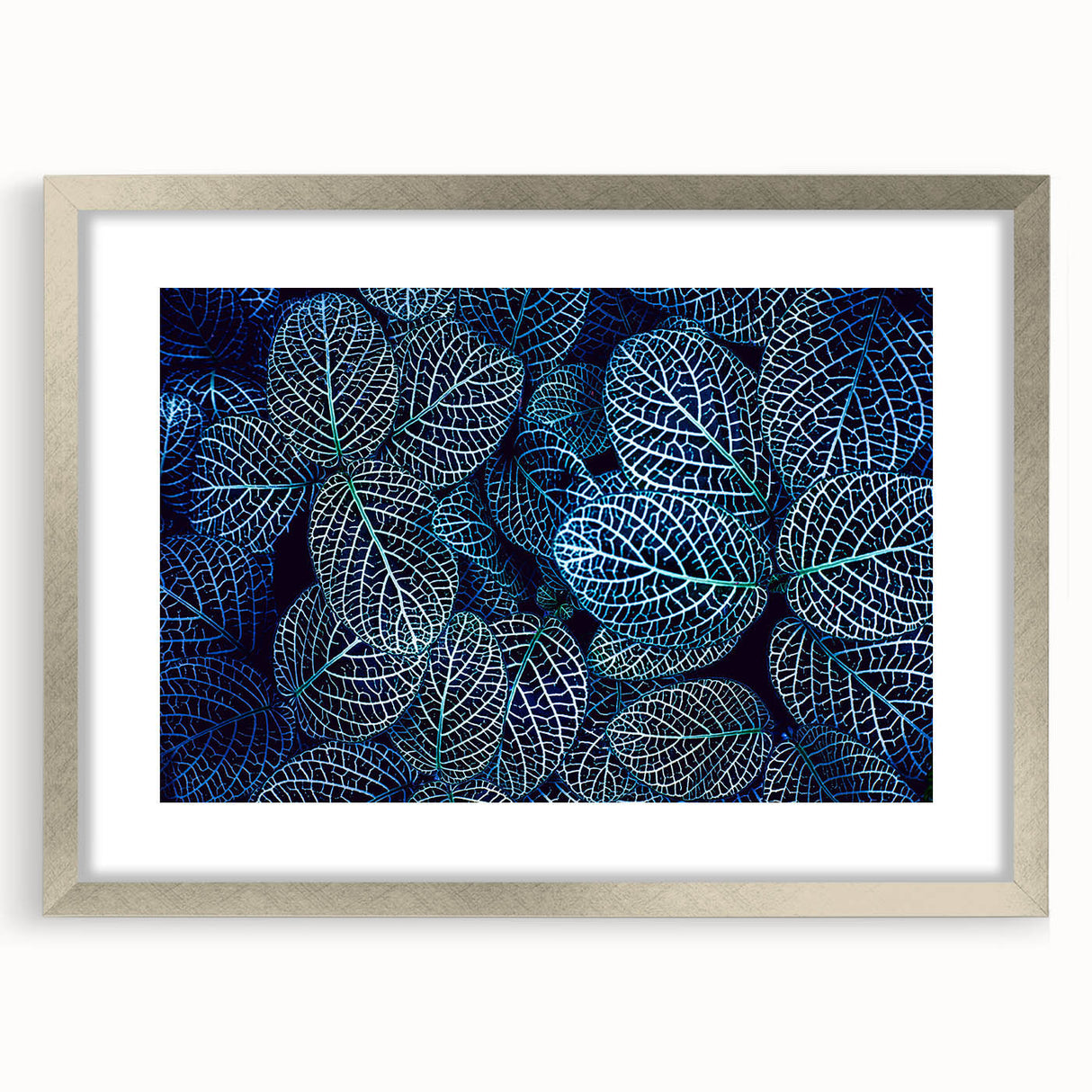 Textured art print of abstract leaves in muted green and brown shades, framed in silver, ideal for bedroom decor.