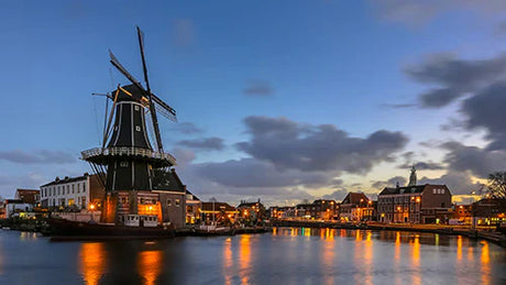 Night view of Amsterdam city with windmill, waterway, and architectural beauty