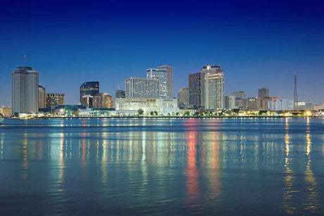 Daytime view of New Orleans' metropolitan area featuring skyscrapers and high-rise buildings by a body of water.