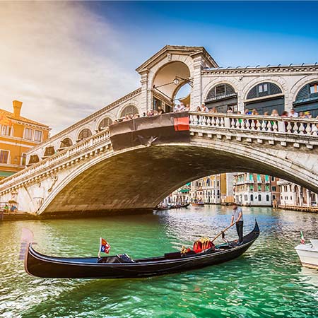 Gondola on Grand Canal beneath Rialto Bridge in Venice, Italy with sunlit buildings – romantic Italian wall art for sophisticated home or office décor.