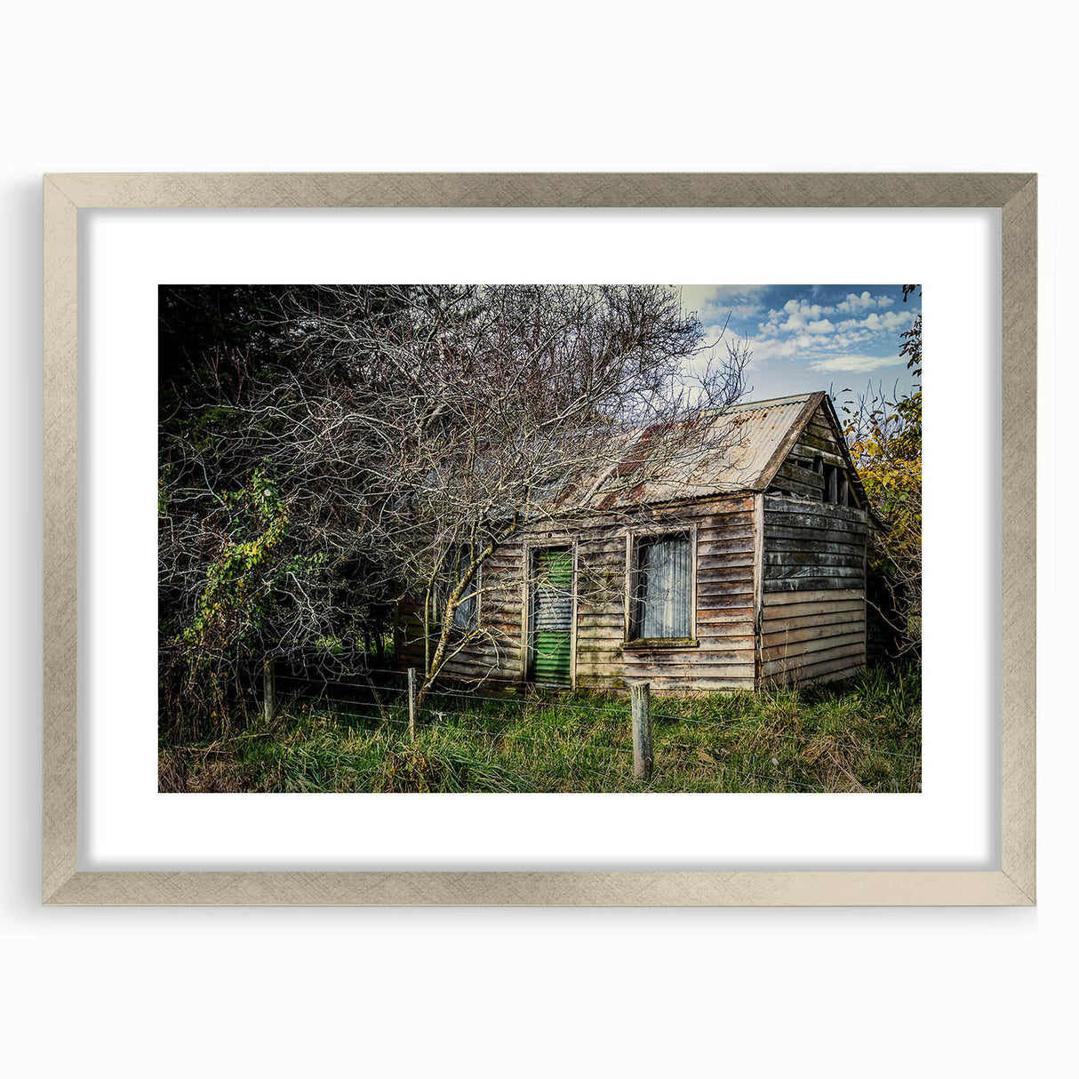 Textured abstract art print showing a dilapidated building in muted gray and silver tones, framed in silver.