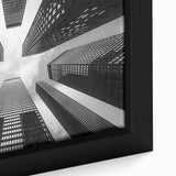 Close-up of a black framed canvas featuring a textured skyscraper design with colorful accents, ideal for living room decor.