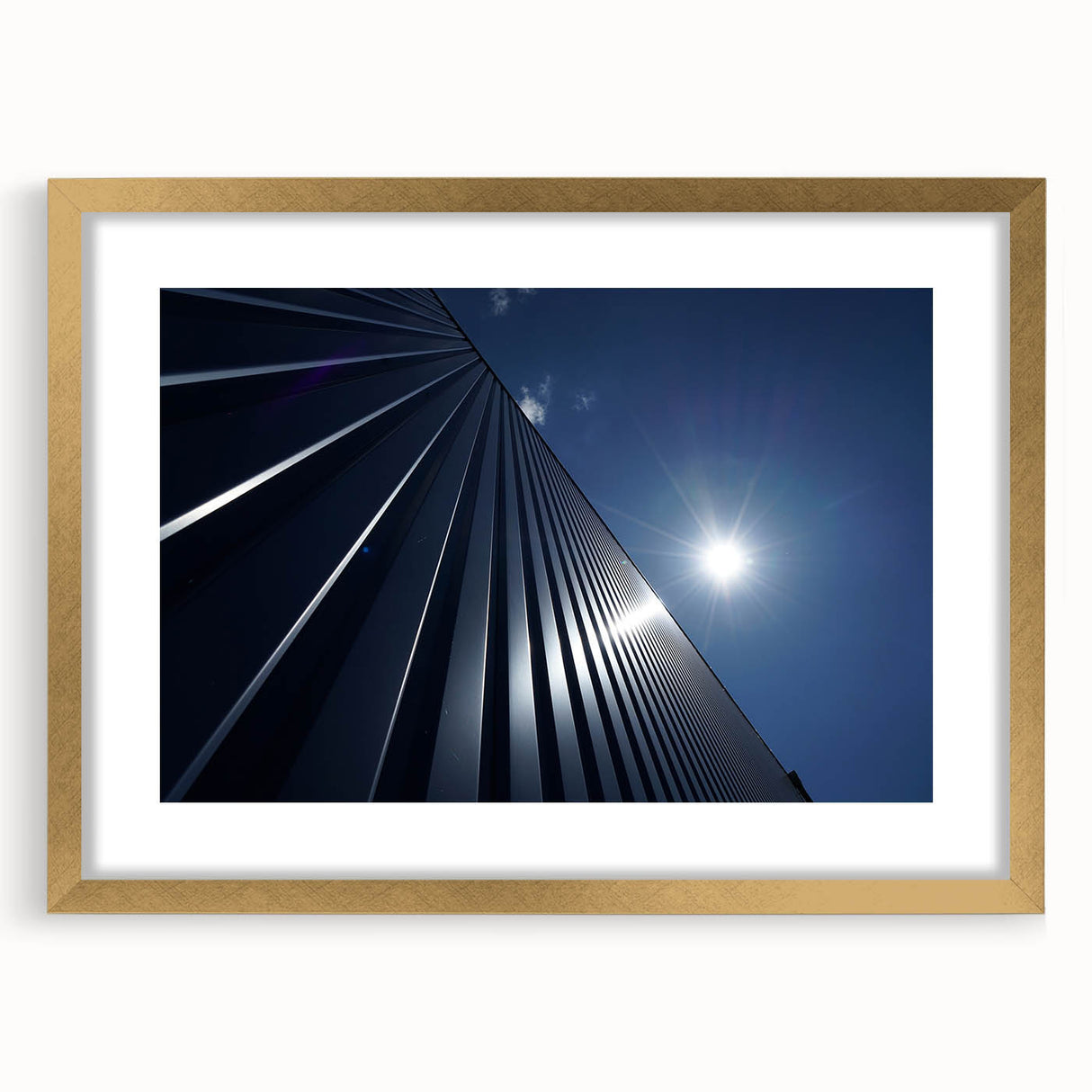 Textured abstract art print of skyscrapers in muted gold and gray tones, framed with a gold mat, suitable for bedroom decor.