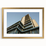 Textured art print of abstract skyscrapers in gold frame, using a palette of gray and blue, suitable for bedroom decor.