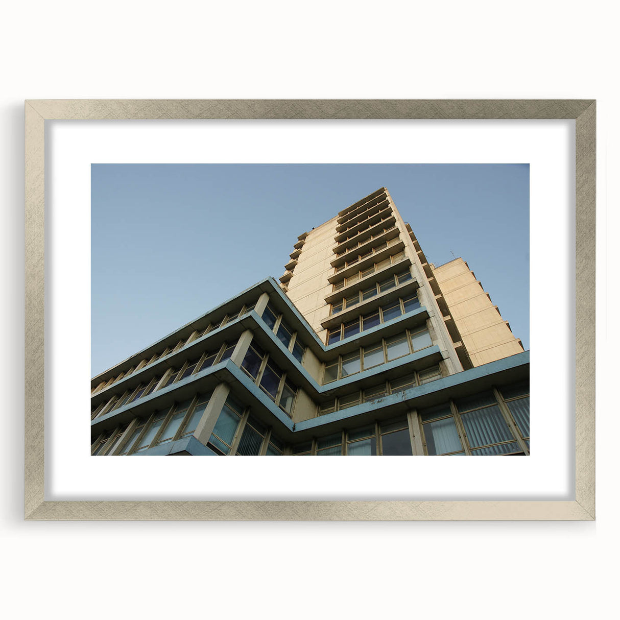 Abstract art print of skyscrapers in muted gray and blue tones on a framed silver mat.