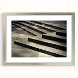 Textured art print of an abstract staircase in muted gray, ideal for modern bedroom decor, framed with a silver mat.