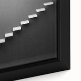 Close-up of a black wall art featuring a textured, colorful staircase design on framed canvas, ideal for living room decor.