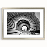 Textured abstract art print of a spiraling staircase in muted gray, framed in silver, ideal for bedroom art.