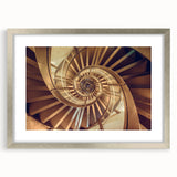 Textured abstract art print of a spiral staircase in muted gray tones on a framed silver mat, ideal for modern bedroom decor.