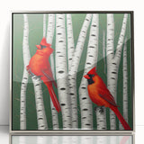 Framed wall art featuring vibrant red cardinal birds perched on branches, set against a silver-accented background, ideal for nature enthusiasts and home decor.