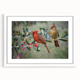Framed wall art featuring vibrant red cardinals perched on branches, accented by green foliage, presented in a sleek white frame with a mat for a polished look. Ideal for nature lovers and home decor enthusiasts.