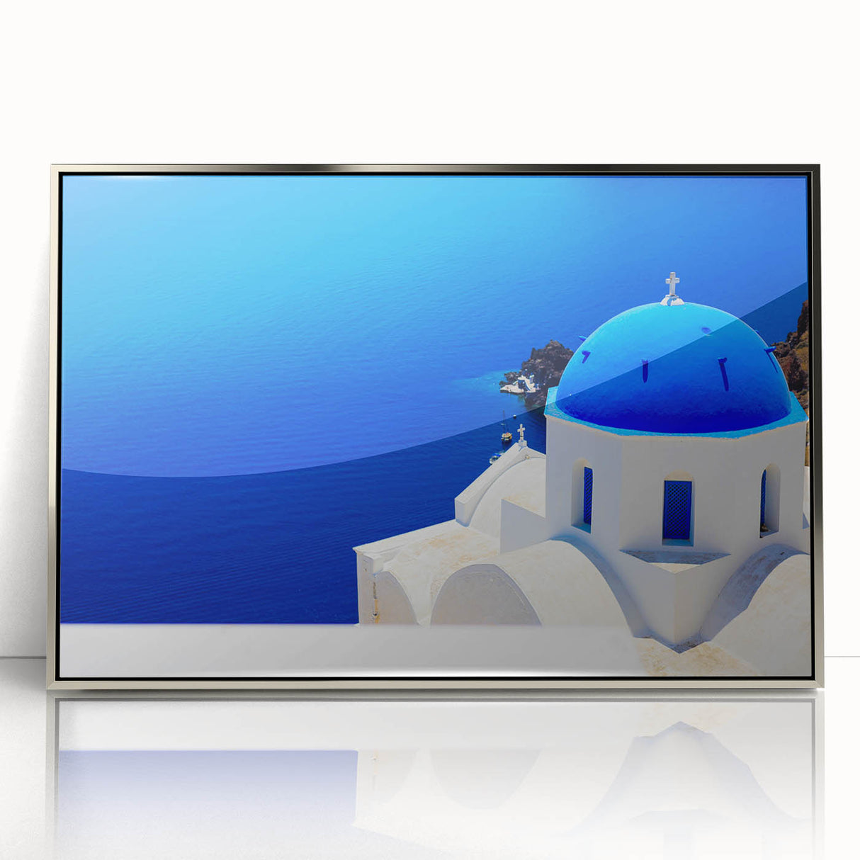 Large art print of Santorini scenery in muted blue and white tones on a silver-framed acrylic.