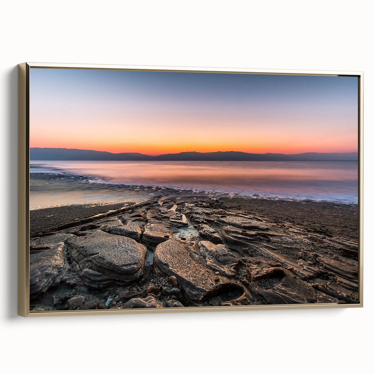 Framed canvas wall art featuring a vintage-style landscape painting of the Dead Sea in muted gold and black tones.