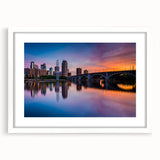 Abstract art print of Minneapolis skyline in muted blue and gray tones on a white framed mat, suitable for dining room decor.
