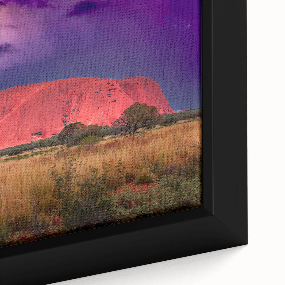Close-up of a textured black wall art featuring Ayers Rock in vibrant colors on a framed canvas.