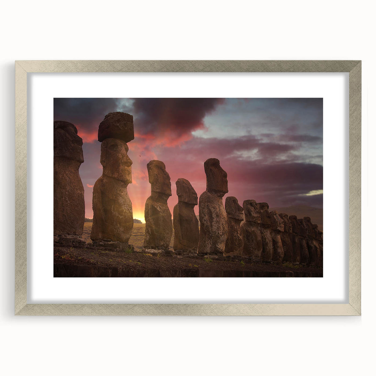Textured art of Easter Island statues on silver-framed, matted print, ideal for bedroom wall decor.
