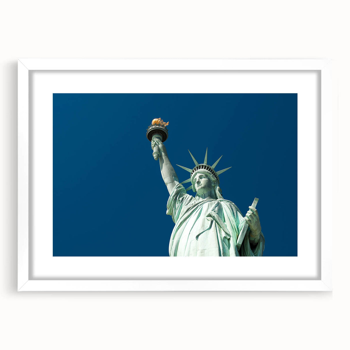 Abstract art print of the Statue of Liberty in muted blue tones on a white framed poster, suitable for dining room decor.