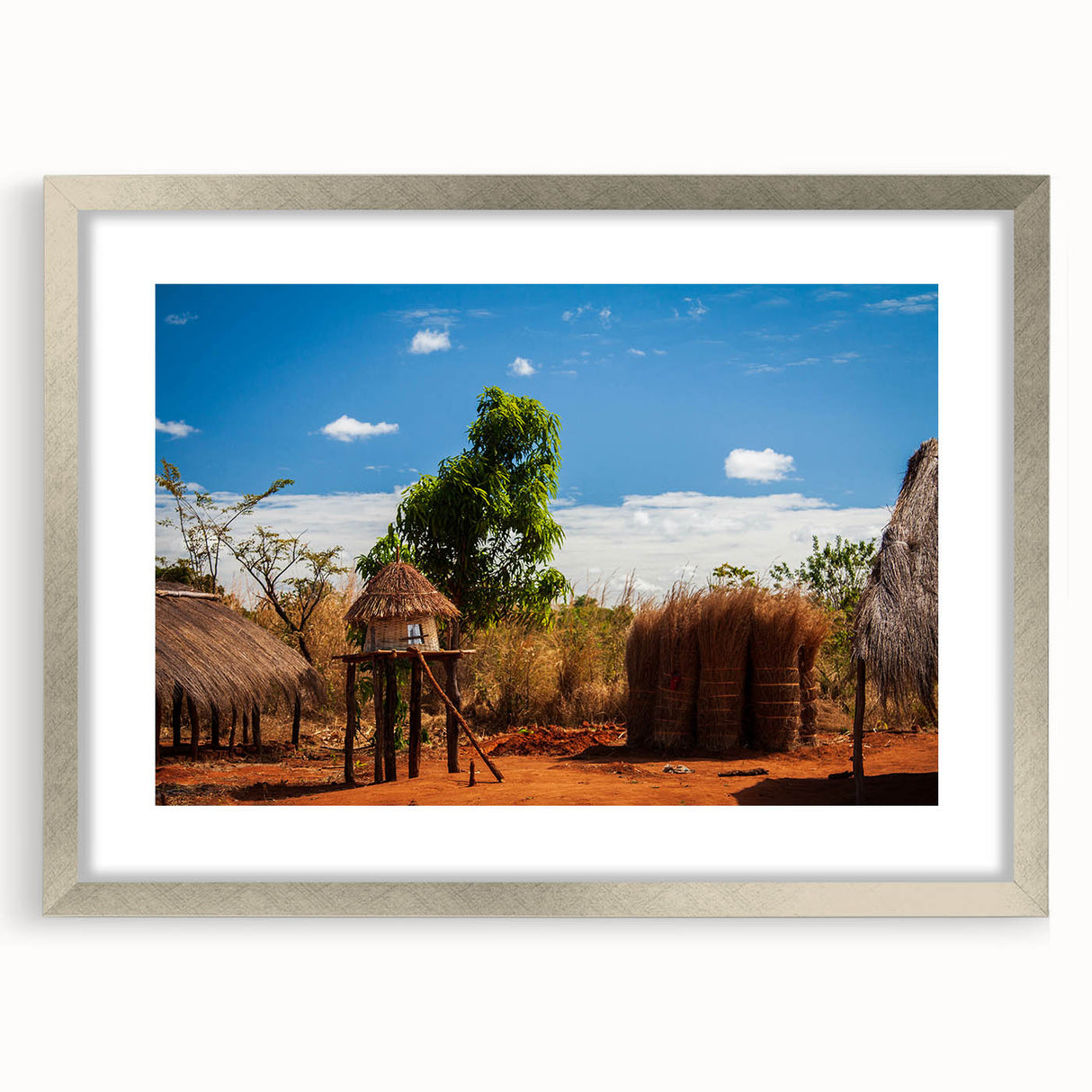 Textured abstract art print of an African scenery in muted earth tones on a framed silver mat, suitable for bedroom decor.