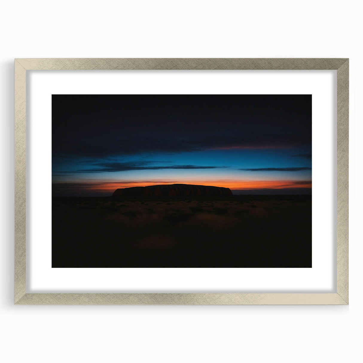 Abstract art print of Ayers Rock in muted orange and brown tones, framed in silver, suitable for dining room decor.