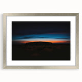 Abstract art print of Ayers Rock in muted orange and brown tones, framed in silver, suitable for dining room decor.