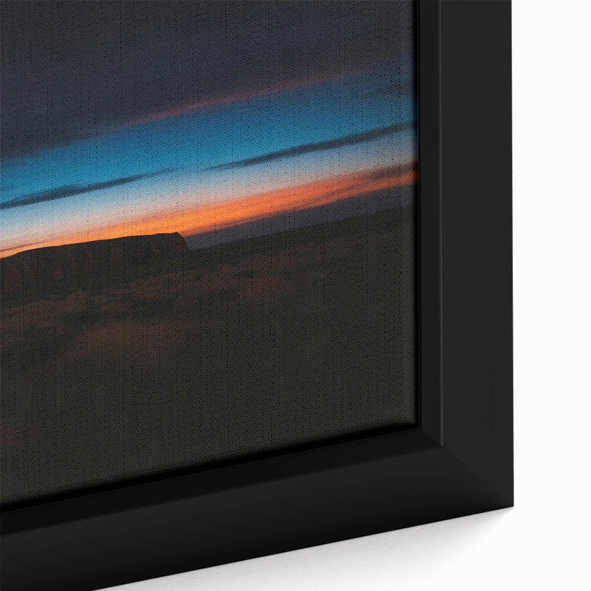 Close-up of a textured black wall art depicting Ayers Rock in Australia on a framed canvas, featuring earthy color tones.