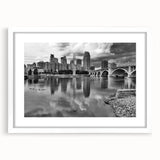 Abstract art print of Minneapolis skyline in muted gray and blue tones on a framed white mat, suitable for dining room decor.