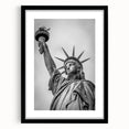 Abstract art print of the Statue of Liberty in muted green and blue tones on a framed black mat.