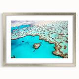 Abstract art print depicting the Great Barrier Reef in vibrant blue and green tones on a framed silver mat.