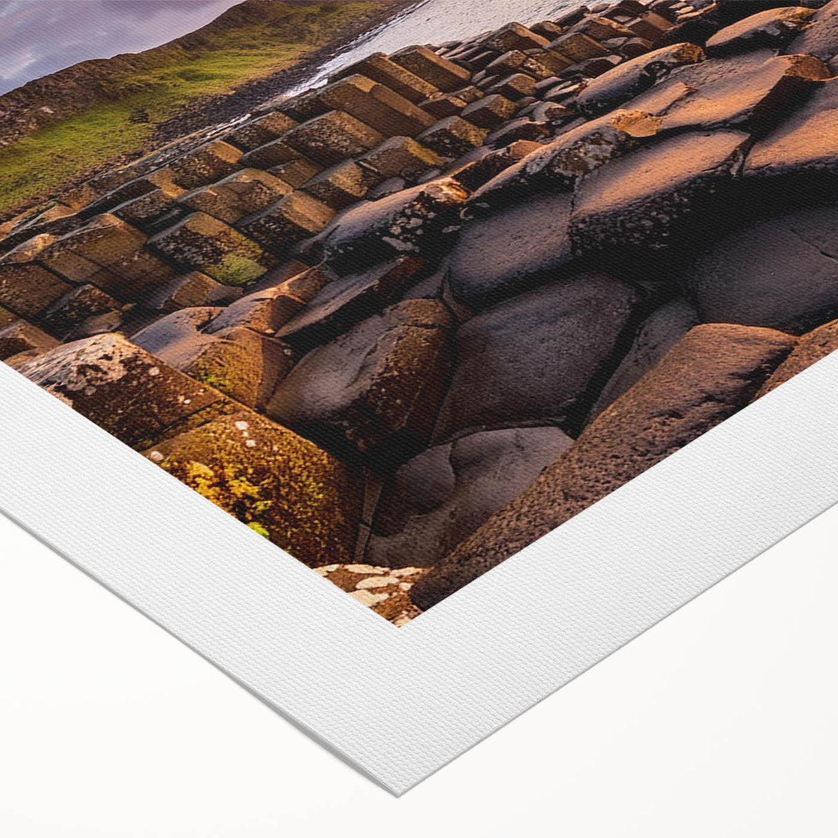 Art deco poster depicting the rugged coastline of Northern Ireland in muted green and blue tones on rolled canvas.