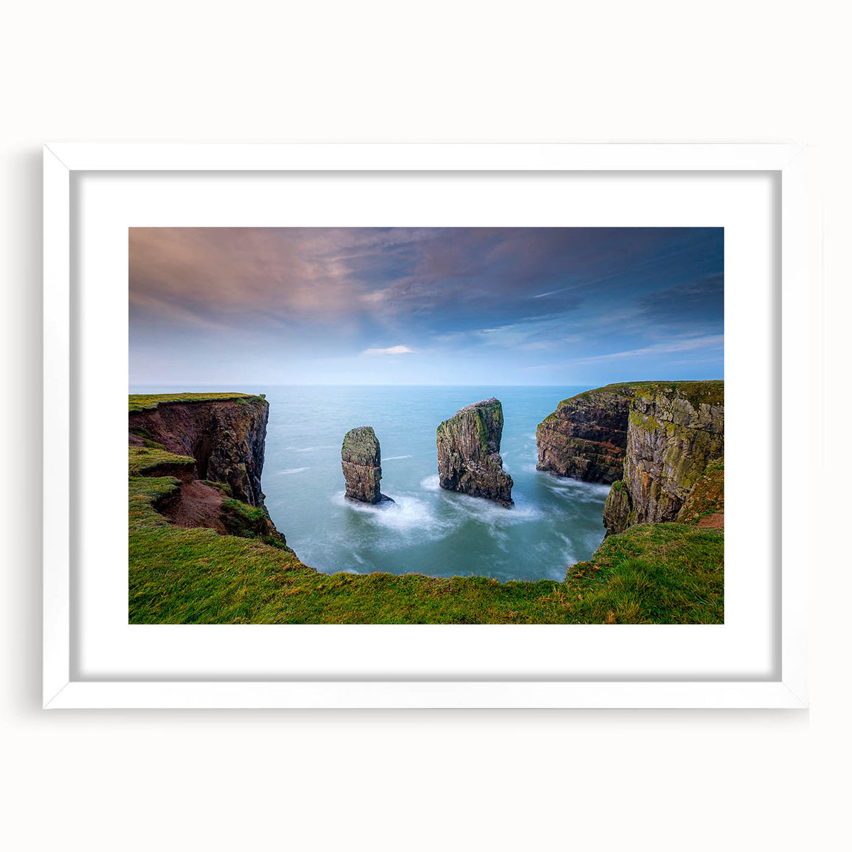Abstract art print of a Welsh landscape in muted green and blue tones, framed with a white mat.