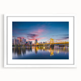Abstract art print of Pittsburgh skyline in muted gray and blue tones on a framed white mat, suitable for dining room decor.