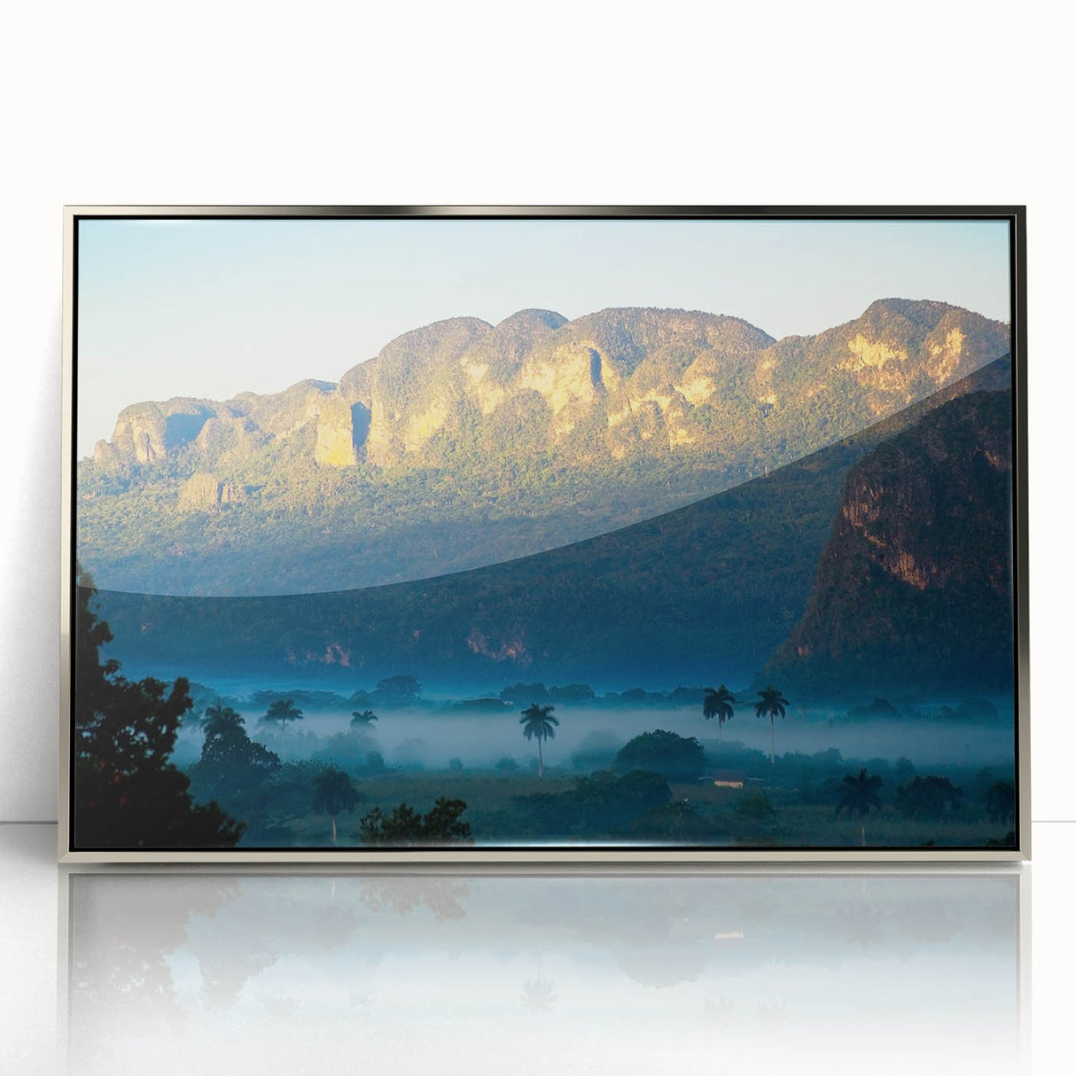 Large art print of a Caribbean scenery in muted blue and green tones on a silver-framed acrylic.