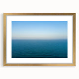Abstract art print of the Mediterranean Sea in muted blue and white tones, framed in gold, suitable for dining room decor.