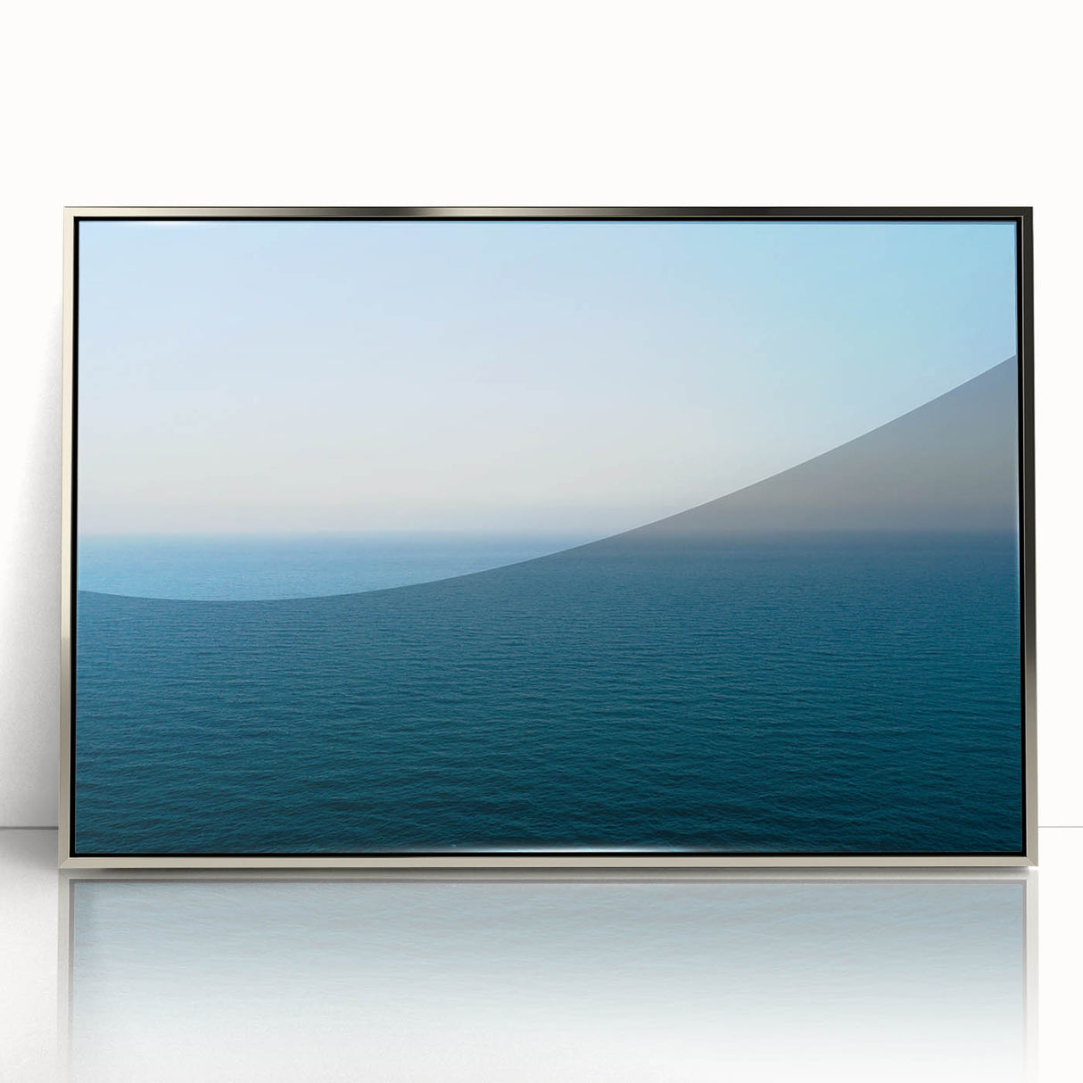Large acrylic print of Mediterranean sea landscape in muted blue and white tones, framed in silver.