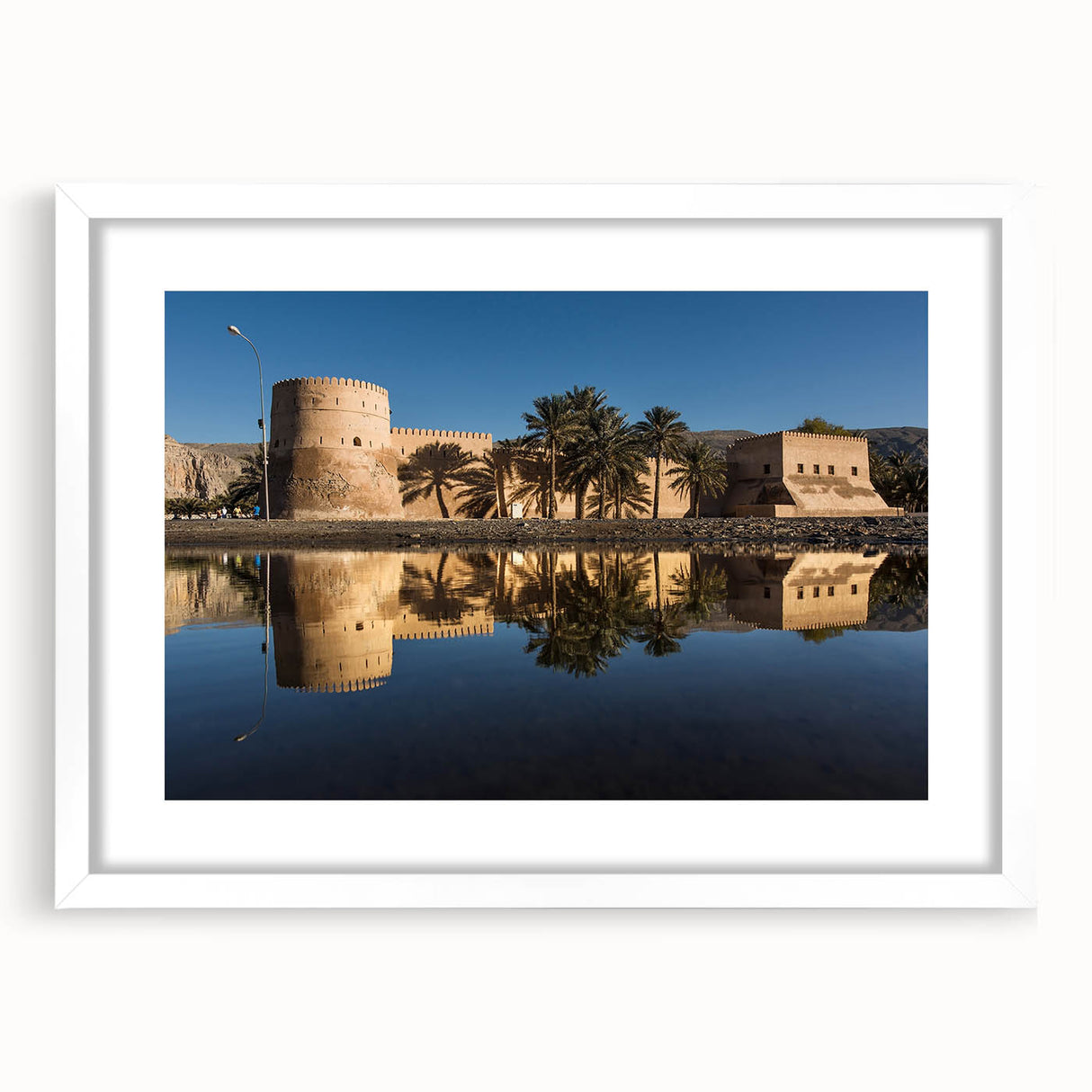 Abstract art print featuring a stylized Oman scenery in earth tones on a white-matted frame, suitable for dining room decor.