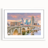 Abstract art print of Minneapolis skyline in muted blue and gray tones on a framed white mat, ideal for dining room decor.