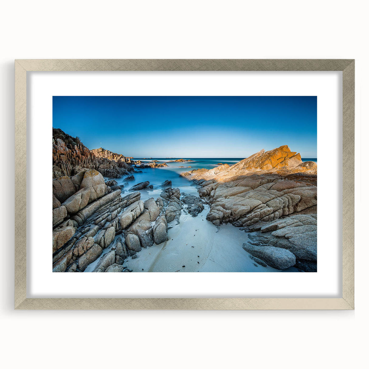 Abstract art print depicting a Tasmanian landscape in muted green and brown tones, framed in silver.