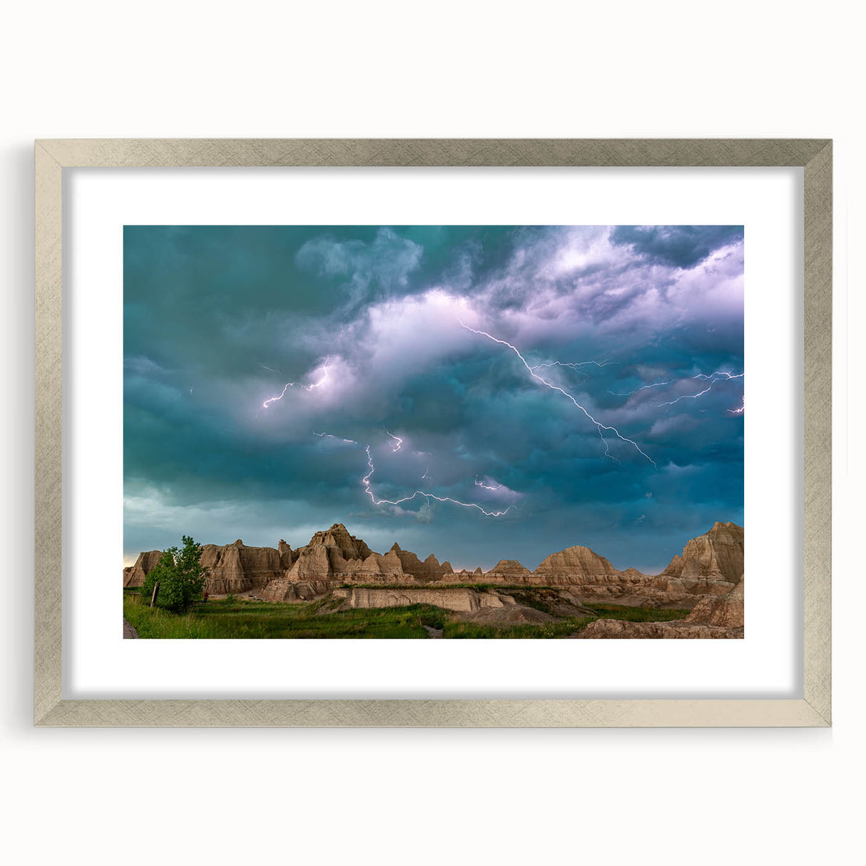 Textured art print of South Dakota Badlands in muted earth tones on a silver-framed mat, suitable for bedroom decor.