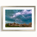 Textured art print of South Dakota Badlands in muted earth tones on a silver-framed mat, suitable for bedroom decor.