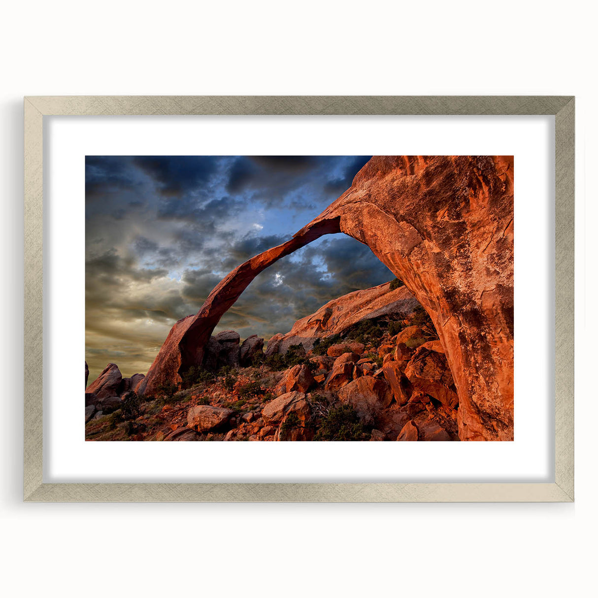 Textured art depicting Arches National Park in muted earth tones on a framed silver mat, suitable for bedroom decor.