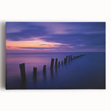 Stretched canvas artwork depicting a serene beach landscape at sunset, featuring vibrant colors of orange and blue, perfect for home decor or coastal-themed spaces.