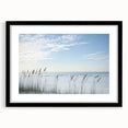 Black-framed landscape artwork showcasing a serene beach scene with soft waves and a clear sky, featuring a white mat for an elegant presentation, perfect for home decor.