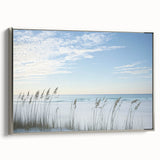 Framed landscape canvas depicting a serene beach scene with soft waves and a vibrant sunset, showcasing a silver frame that enhances its elegant appeal. Perfect for coastal-themed decor.