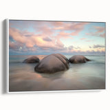 Framed canvas artwork showcasing a serene beach landscape, featuring soft waves and a vibrant sunset, presented in a sleek white frame, perfect for coastal decor.